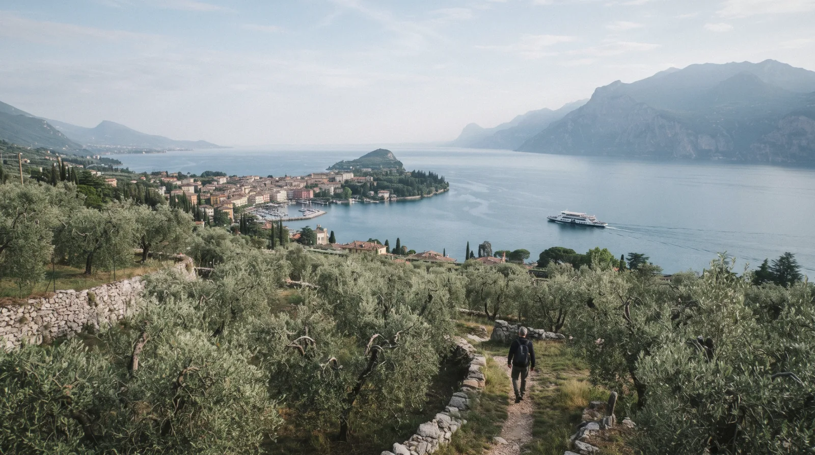 Olive terraces above Garda town and a ferry crossing Lake Garda, Italy, on a clear late-May morning