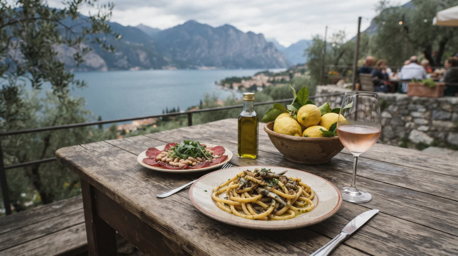 Bigoli with lake fish, carne salada and Chiaretto on a terrace table above the water, Lake Garda food, Italy