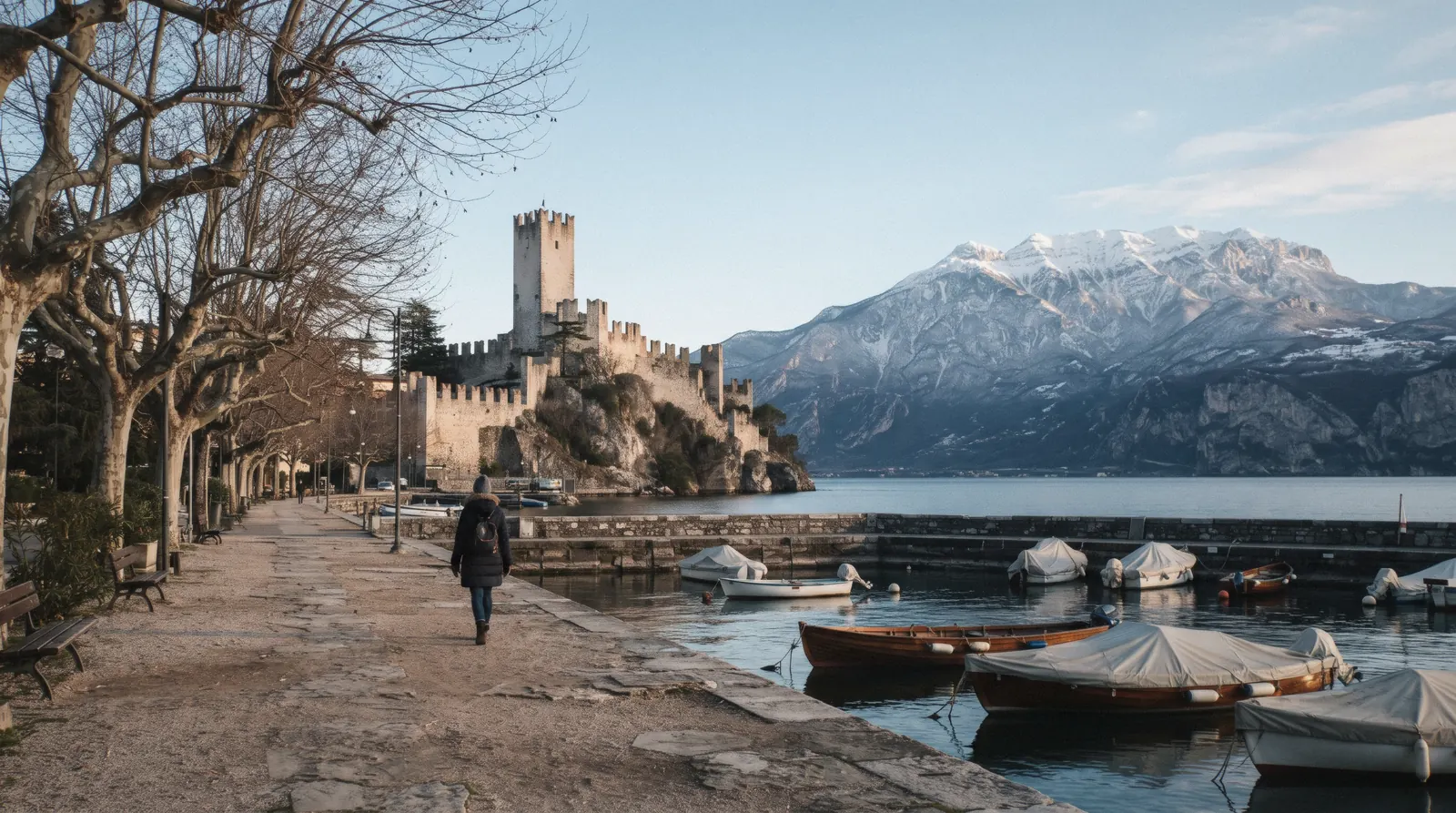 Malcesine castle above still water and snow on Monte Baldo, Lake Garda, Italy, on a cold January afternoon
