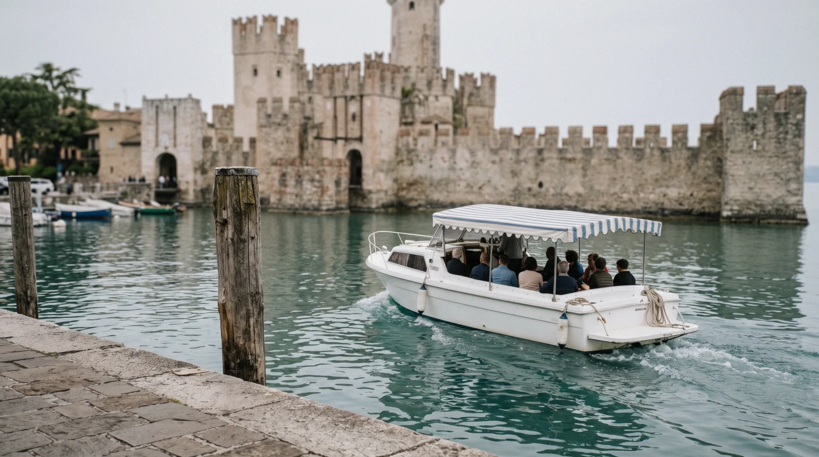 A tour boat leaving the castle harbour at Sirmione in the morning, one of the Lake Garda tours, Italy