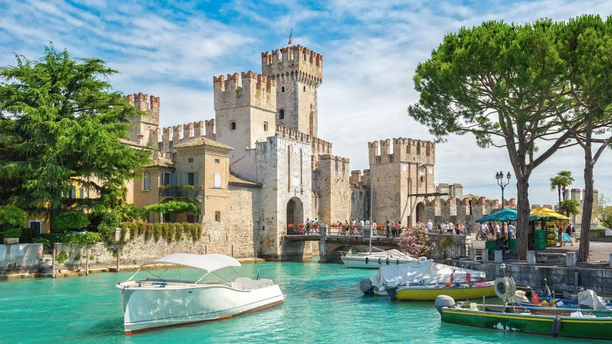 Scaliger Castle in Sirmione with its swallowtail battlements above a harbour of small white boats