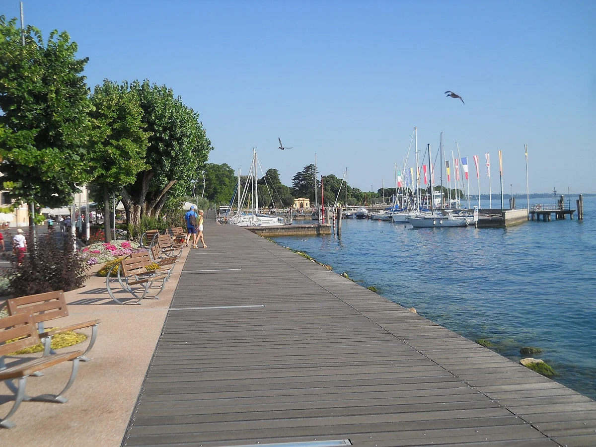 The lakefront boardwalk at Bardolino on Lake Garda, Italy, with flower beds and the marina in spring sun