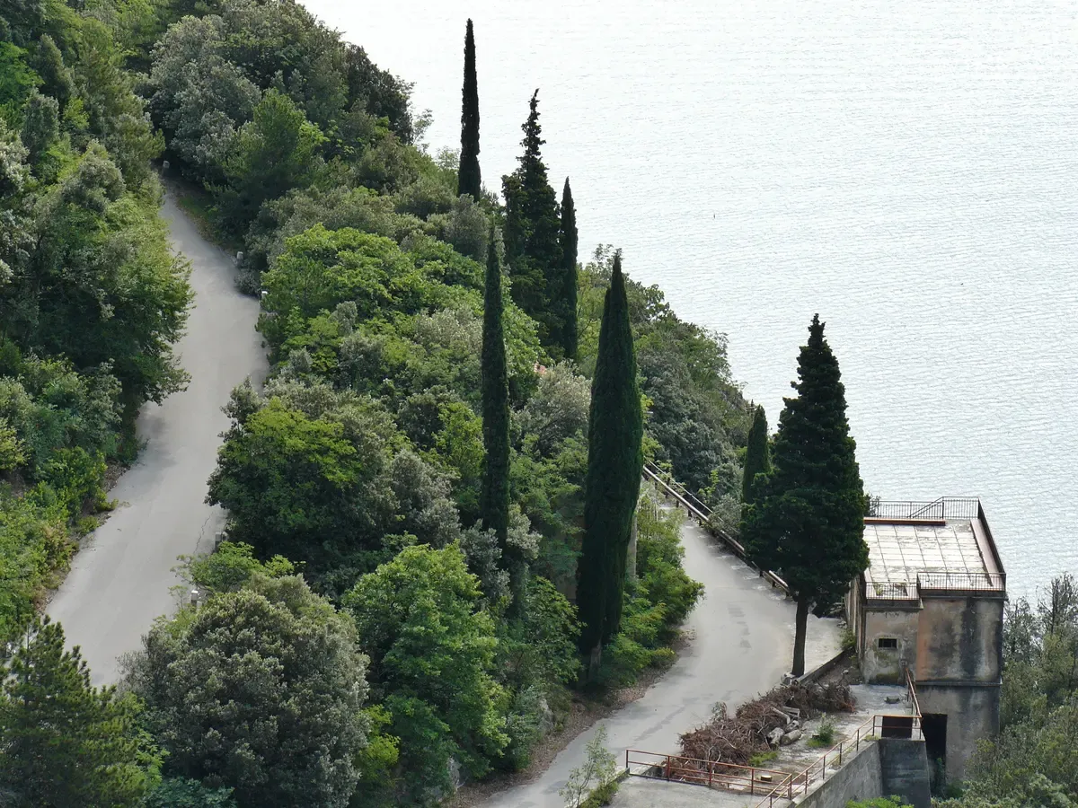 The old Ponale road winding between cypresses above Lake Garda near Riva del Garda, Italy
