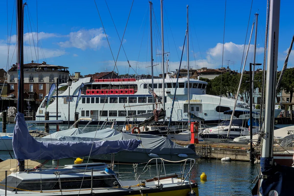 A lake ferry docked behind sailboats in the harbor of Desenzano del Garda