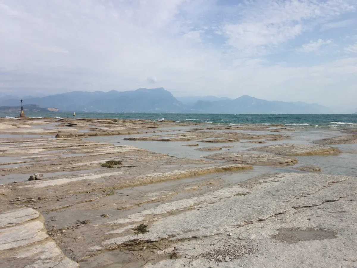 Flat limestone slabs at Jamaica Beach below the Grottoes of Catullus in Sirmione, one of the Lake Garda beaches, Italy