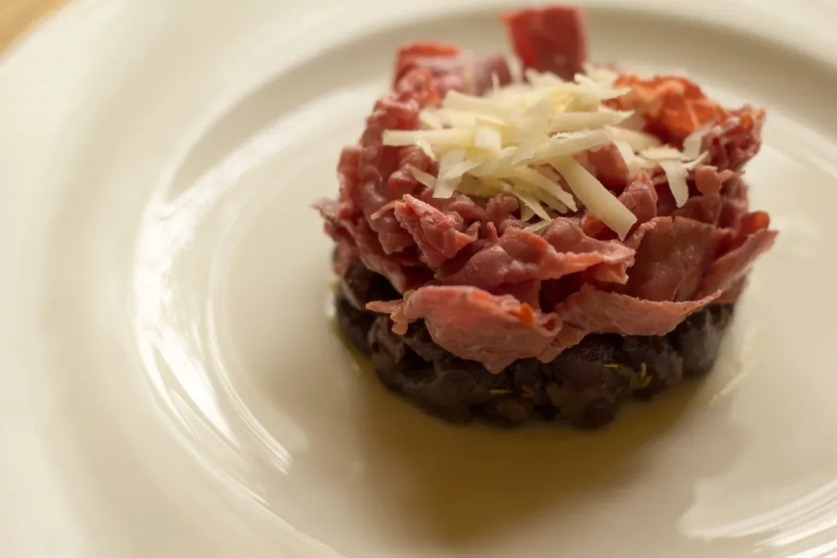 A plate of carne salada over beans, a Trentino dish of the Lake Garda food tradition, Italy