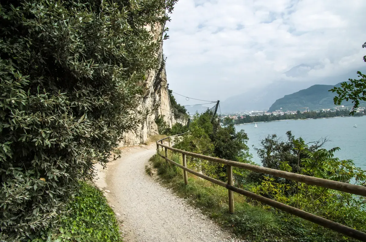 A gravel path with a wooden rail on the cliff above the water near Riva del Garda, Lake Garda, Italy