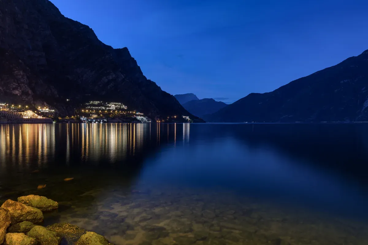 Lake Garda at dusk from the shore of Limone sul Garda, Italy, the lights of the town reflected in the water