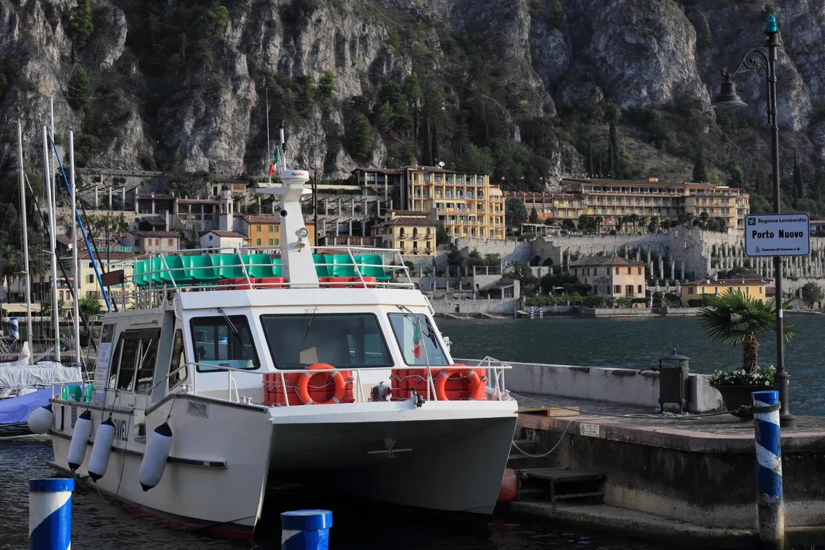 The Porto Nuovo of Limone sul Garda on Lake Garda, Italy, with a motorboat at the quay and the town under the cliff