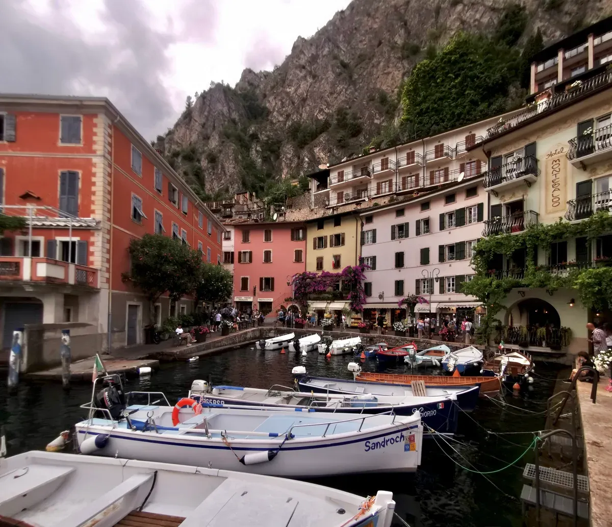 Fishing boats in the small harbor of Limone sul Garda under pastel houses and cliffs