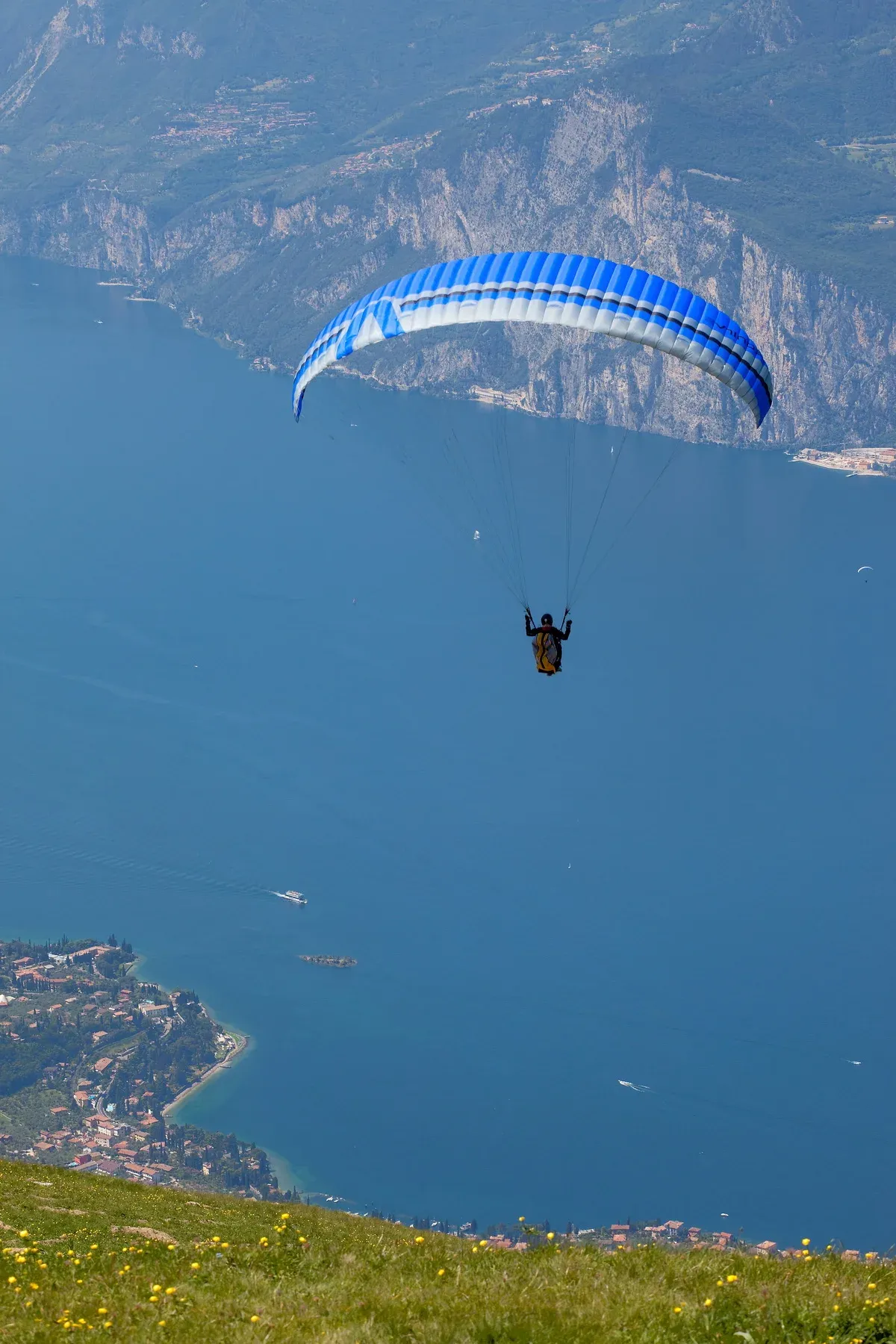 A paraglider over Lake Garda after launching from Monte Baldo, with the Malcesine shore below, Italy
