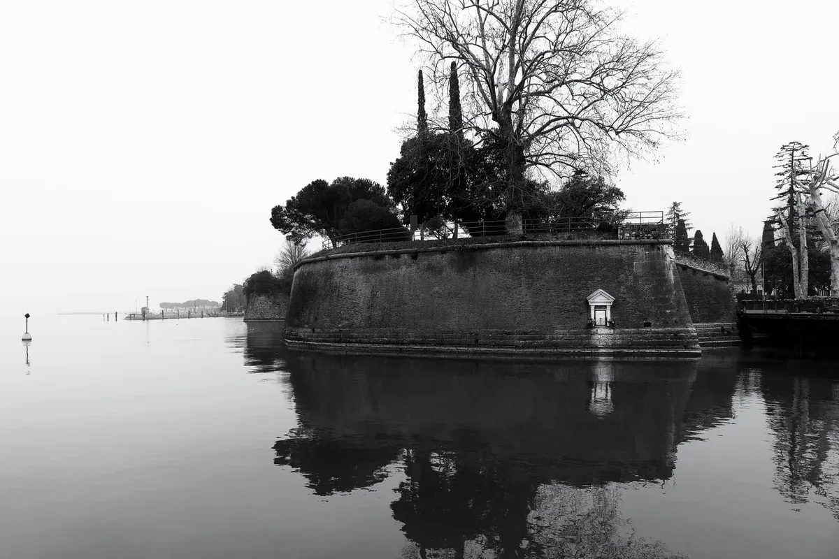 The pentagonal walls of the Peschiera del Garda fortress reflected in still water