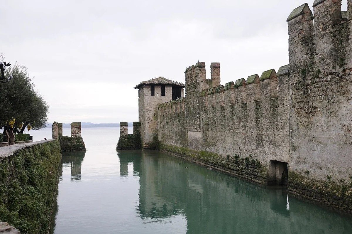 The walls and fortified dock of the Scaligero Castle opening onto the water on a Sirmione boat trip, Lake Garda, Italy