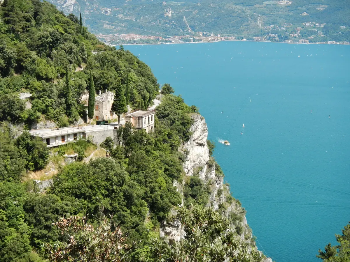 The old Ponale road cut into the cliff above Lake Garda with the Belvedere building and Riva del Garda bay below, Italy